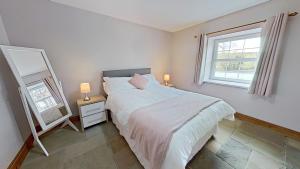 a white bedroom with a bed and a mirror at The Barn. in Carmarthen