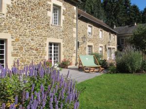 a stone building with a bench and purple flowers at Le Coteau du Seigneur in Laize-la-Ville