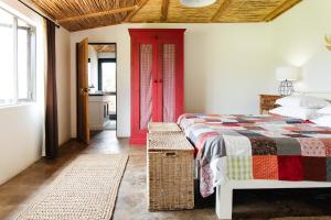 1 dormitorio con 1 cama y puerta roja en The Cowshed en Lydenburg