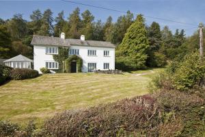 una casa blanca en una colina con un patio en High Grassings Country House en Ambleside