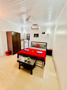 a bedroom with a red bed and a table at Blue Mirage Palolem Goa in Canacona