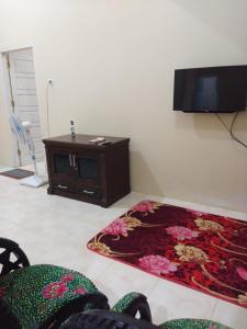 sala de estar con TV y alfombra de flores en Vila Anggur Pintukabun, en Bukittinggi