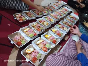 a table with many trays of food on it at Vila Anggur Pintukabun in Bukittinggi