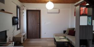 ein Wohnzimmer mit einem Sofa und einer Holztür in der Unterkunft Μονοκατοικία Σουρωτή in Sourotí