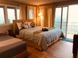 een slaapkamer met een bed en een balkon met ramen bij บ้านบนภู ปากช่อง พลูวิลล่า - with a housekeeper in Ban Lam Thong Lang +38 foto's