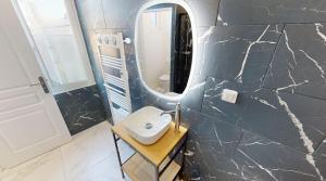 een badkamer met een wastafel en een spiegel bij Les meublés touristiques - Saint Théodore en face du Louvre-Lens in Lens