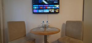 a table with two chairs and a tv on a wall at City break Park Studio Bucharest in Bucharest