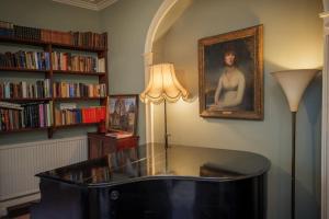 a library with a table and a portrait of a woman at Gelly Dylan Thomas Paradise in Lampeter