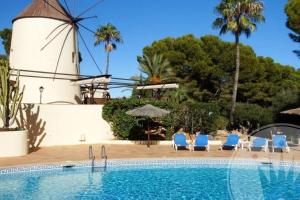 een zwembad met stoelen en een windmolen op de achtergrond bij La Manga Club Resort - Los Molinos 20 in Atamaría