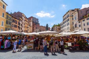 un groupe de personnes se tenant sur un marché avec des parapluies dans l'établissement Theatrum Domus Pompei, à Rome