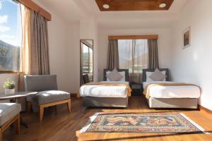 a room with two beds and a table and chairs at Hotel Dralha in Thimphu