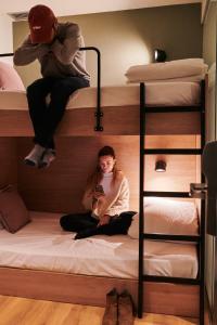 two people sitting on bunk beds looking at a cell phone at TOC Hotel Las Ramblas in Barcelona