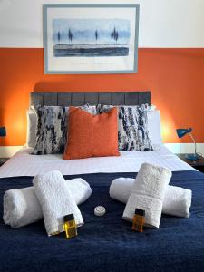 a bed with white pillows and an orange wall at Hindmarsh Apartment in Ashington