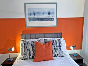a bed with an orange headboard and two lamps at Hindmarsh Apartment in Ashington
