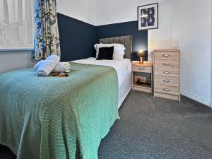 a bedroom with a large bed and a dresser with a bed sidx sidx sidx at Hindmarsh Apartment in Ashington