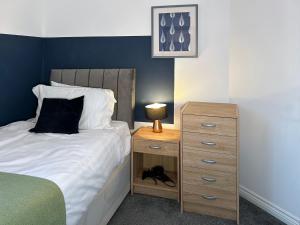 a bedroom with a bed and a nightstand with a black dog sitting next to at Hindmarsh Apartment in Ashington