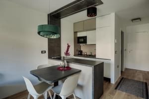 cocina con mesa negra y sillas blancas en Apartma Vitalis, en Smarjeske Toplice