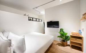 biała sypialnia z łóżkiem i telewizorem w obiekcie Donggang Jingdi B&B w mieście Donggang