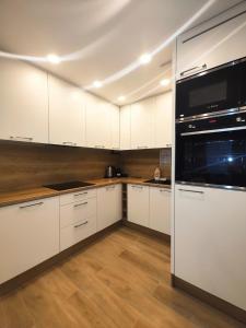 uma cozinha com armários brancos e um aparelho preto em Maya's Flats & Resorts 42 - Świętej Barbary em Gdansk