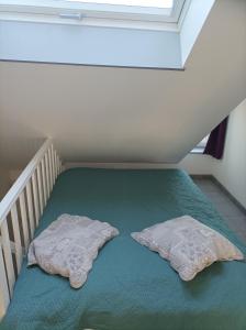 2 almohadas en una cama en una habitación pequeña en Près des etoiles, en Dieppe