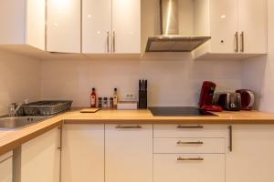 une cuisine avec des placards blancs et un comptoir dans l'établissement Le Beau Refuge Parisien de Cergy - Parisian modern flat at Cergy, à Cergy