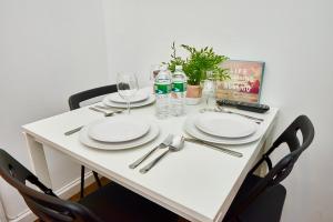 - une table blanche avec des assiettes et des verres à vin dans l'établissement Cozy FamilyFriendly Apartment with 2 Bedrooms, à New York