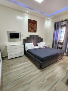a bedroom with a bed with a television and a dresser at F3 Appartement Point E Dakar in Dakar