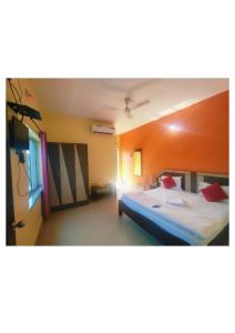 1 dormitorio con 1 cama grande y pared de color naranja en Goroomgo D2 Holiday inn Near Sea Beach, en Puri