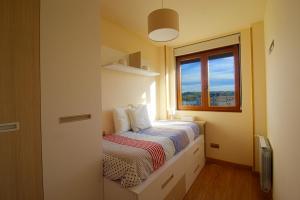 a small bedroom with a bed and a window at La Casa del Muelle in Suances