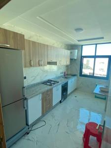 Il comprend une cuisine dotée d'un sol en marbre blanc et d'un réfrigérateur blanc. dans l'établissement Holikeys - Fès - 3 Ch - Lot Brdai 003, à Fès