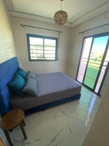 um quarto com uma cama, uma cadeira e 2 janelas em Holikeys - Fès - 3 Ch - Lot Brdai 003 em Fez