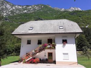 a white house with flowers on the stairs at Apartma pod Rožem in Soča