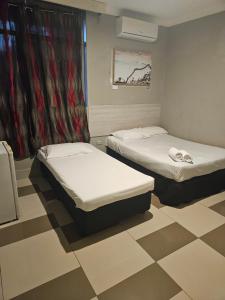 two twin beds in a room with a checkered floor at Perth City Motel in Perth