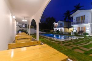 a row of wooden benches next to a swimming pool at night at Tvessa - A Boutique Hotel in Mandrem