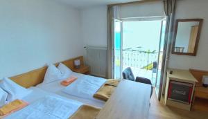 1 dormitorio con cama, mesa y balcón en Gasthof mit Seeterasse & Appartements Zur Landeroith en Weyregg