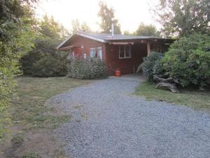 a red house with a gravel driveway in front of it at Arriendo casa Verano Pucón in Pucón
