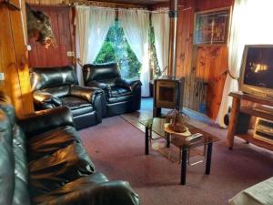 a living room with a leather couch and a table at Arriendo casa Verano Pucón in Pucón