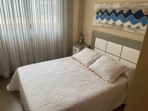 Un dormitorio con una cama blanca y una pintura en la pared en PISO DE LUJO EN TORRENOSTRA, en Torreblanca