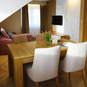 a dining room with a wooden table and white chairs at Apartamenty u Roxi in Jelenia Góra