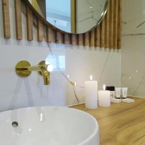 a bathroom with a sink and a mirror and candles at Apartamenty u Roxi in Jelenia Góra