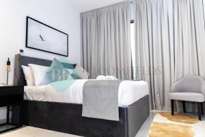 a bedroom with a bed and a chair at Spectacular 2 Bedroom In Oasis in Al Qurayyah