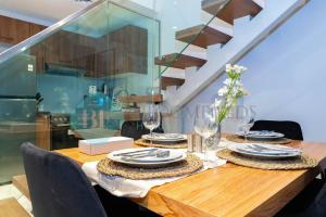 a wooden table with plates and wine glasses on it at Spectacular 2 Bedroom In Oasis in Al Qurayyah