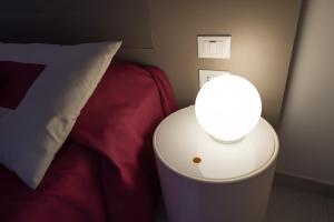 um candeeiro sobre uma mesa ao lado de uma cama com uma almofada em Zenit Hotel em Giulianova