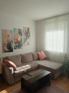 a living room with a couch and paintings on the wall at Alacaster G apartman in Novi Sad