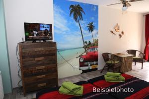 a bedroom with a tv and a painting of a beach at Pension Cubana in Rothenburg