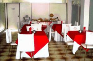 a dining room with red and white tables and chairs at Hotel Aliança in Vila Velha