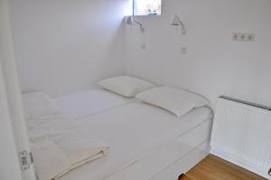 een wit bed met twee kussens erop bij Garnekuul 72 in Callantsoog