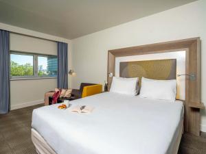 ナントにあるノボテル ナント サントル ガレの白い大型ベッドと椅子が備わるホテルルームです。