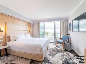 Habitación de hotel con cama y TV en Novotel Sydney Brighton Beach en Sídney