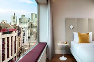 a bedroom with a window with a view of a city at Avani Frankfurt City Hotel - previously NH Collection Frankfurt City in Frankfurt/Main
